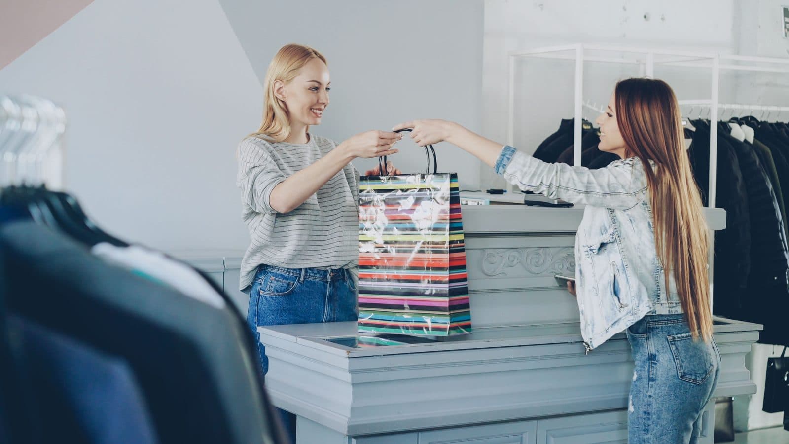 Une vendeuse remet un sac à une cliente en boutique
